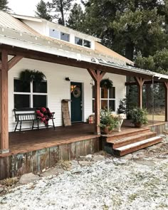 a small white house with porch and covered in snow