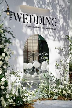 the wedding sign is surrounded by flowers and greenery in front of a white building