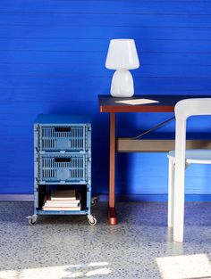 a table with a lamp next to it and a blue wall in the back ground