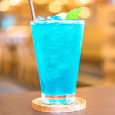 a blue drink with a mint garnish on the rim sitting on a table