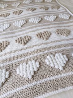 a crocheted blanket with hearts on it sitting on top of a white bed