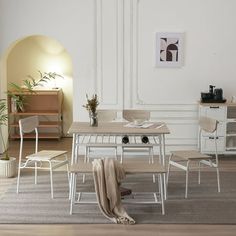 a dining room table and chairs in front of a white wall