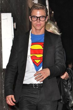 a man wearing a superman t - shirt and black suit with a white tee underneath