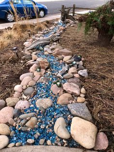 a blue car is parked next to a rock and gravel path that has been made from rocks