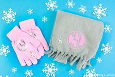 two pink and gray mittens sitting on top of a blue background with snowflakes