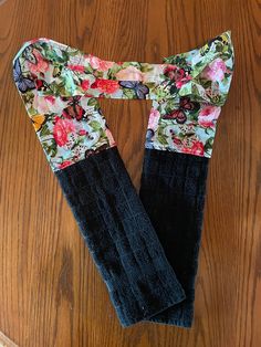 two black gloves with floral print on them sitting on top of a wooden table next to a pair of scissors