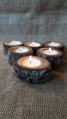 four tea lights are sitting on a table cloth with some wood slices in the middle