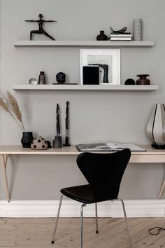 a desk with two shelves above it and a black chair in front of the table