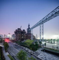 an industrial area with lots of tall buildings next to a river at dusk or dawn