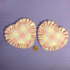 two heart shaped plates with ruffled edges on a purple surface next to a penny