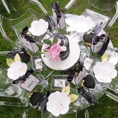 a table topped with lots of clear chairs covered in flowers and small boxes filled with candies