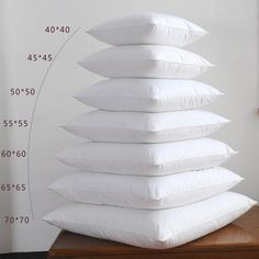 a stack of white pillows sitting on top of a wooden table next to a clock