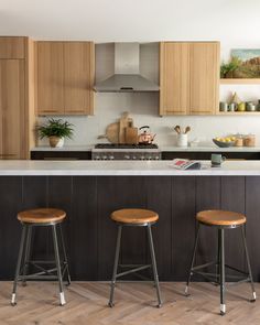 three stools are in front of the kitchen island with an island countertop and wooden cabinets