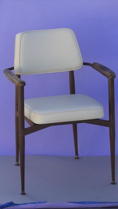 a white chair sitting in front of a purple wall