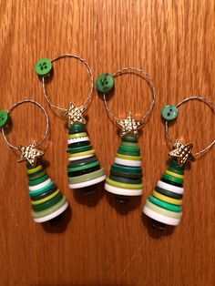 three wine glass charms with green buttons and white, yellow, and green stripes on them