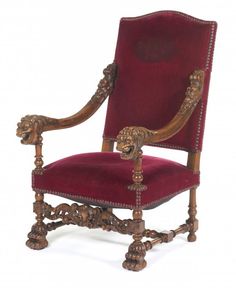 an ornately carved chair with red velvet upholstered back and armrests