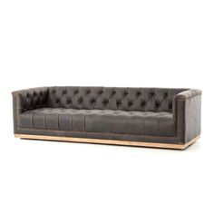 a black leather couch with wooden legs and buttons on the back, in front of a white background