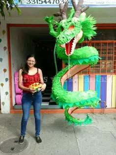 a woman standing in front of a dragon statue holding a plate and smiling at the camera