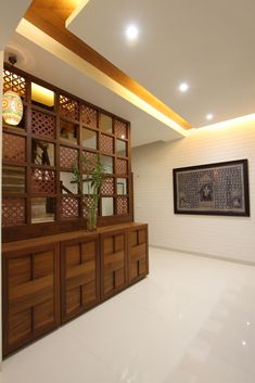 an empty room with a plant in the center and wooden shelves on the wall behind it