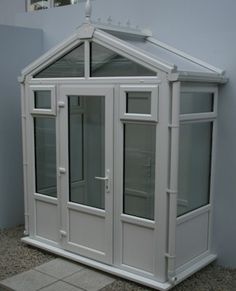 a small white building sitting on top of a tile floor next to a wall and window