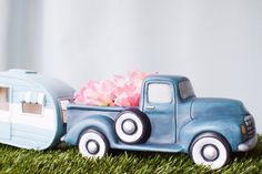 a toy truck with flowers in the back and trailer behind it on some green grass