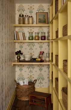 the shelves are full of jars and other items in this room with floral wallpaper