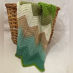 a crocheted pillow sitting on top of a basket next to a white blanket