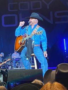 a man with a cowboy hat on singing into a microphone