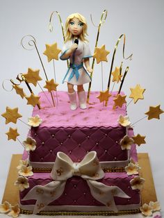 there is a cake that has been decorated with gold stars and a doll on top