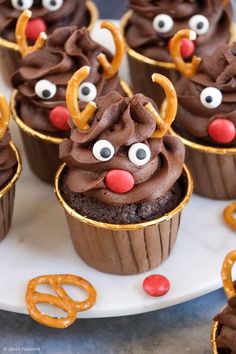 cupcakes with chocolate frosting decorated as reindeer faces and pretzels on a plate