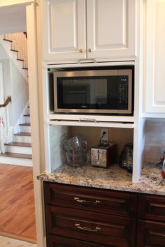 a microwave oven sitting on top of a wooden cabinet in a kitchen next to stairs