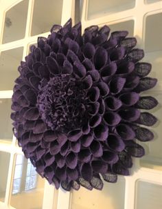 a large purple flower sitting on top of a white wall