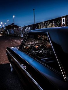 an old car is parked on the side of the road with graffiti all over it