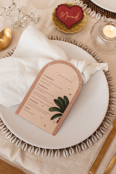 a white plate topped with a menu on top of a table next to gold utensils