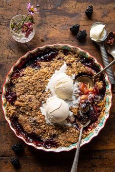 a bowl filled with fruit and ice cream next to two spoons on top of a wooden table