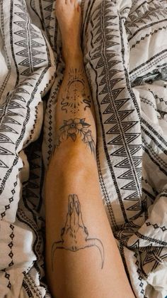 a person laying on top of a bed with a tattoo on their arm and foot