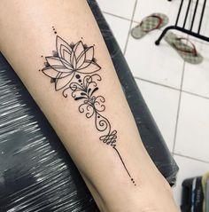 a black and white photo of a flower tattoo on the left arm, with an arrow in the middle