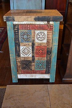 an old wooden box with decorative designs on it's sides, sitting on the floor