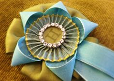 a close up of a blue flower on a yellow cloth with a ribbon around it