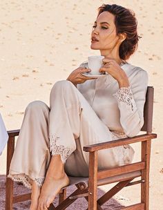 a woman sitting in a chair drinking from a cup