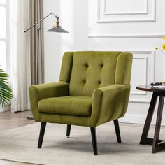 a green chair sitting on top of a rug next to a table with a lamp