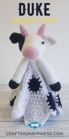 a crocheted cow sitting on top of a wooden floor next to a white wall