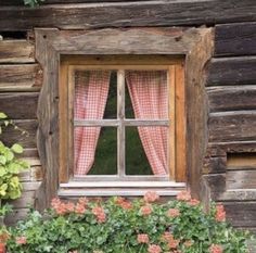 a window with curtains and flowers in front of it