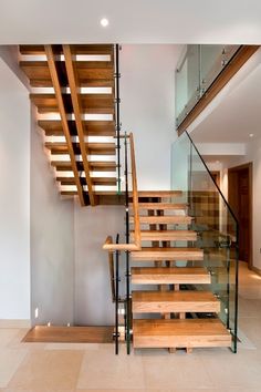 a staircase with glass railing and wooden handrails in a modern style home setting