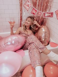 a woman laying in a bathtub surrounded by balloons and streamers with her hand up