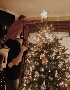 a man and woman decorating a christmas tree