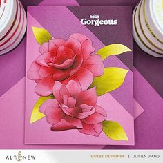 there is a pink card with two flowers on it next to some plates and cups