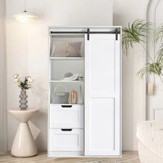 a white cabinet with drawers and shelves in a living room next to a plant on the floor