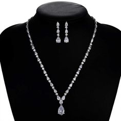 a necklace and earring set on a black mannequinn neckpiece with white stones