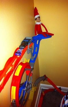 the elf is riding his bike on top of the toy track in the corner by the wall